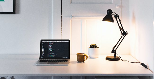 czarna lampka biurkowa oświetlająca biurko z laptopem